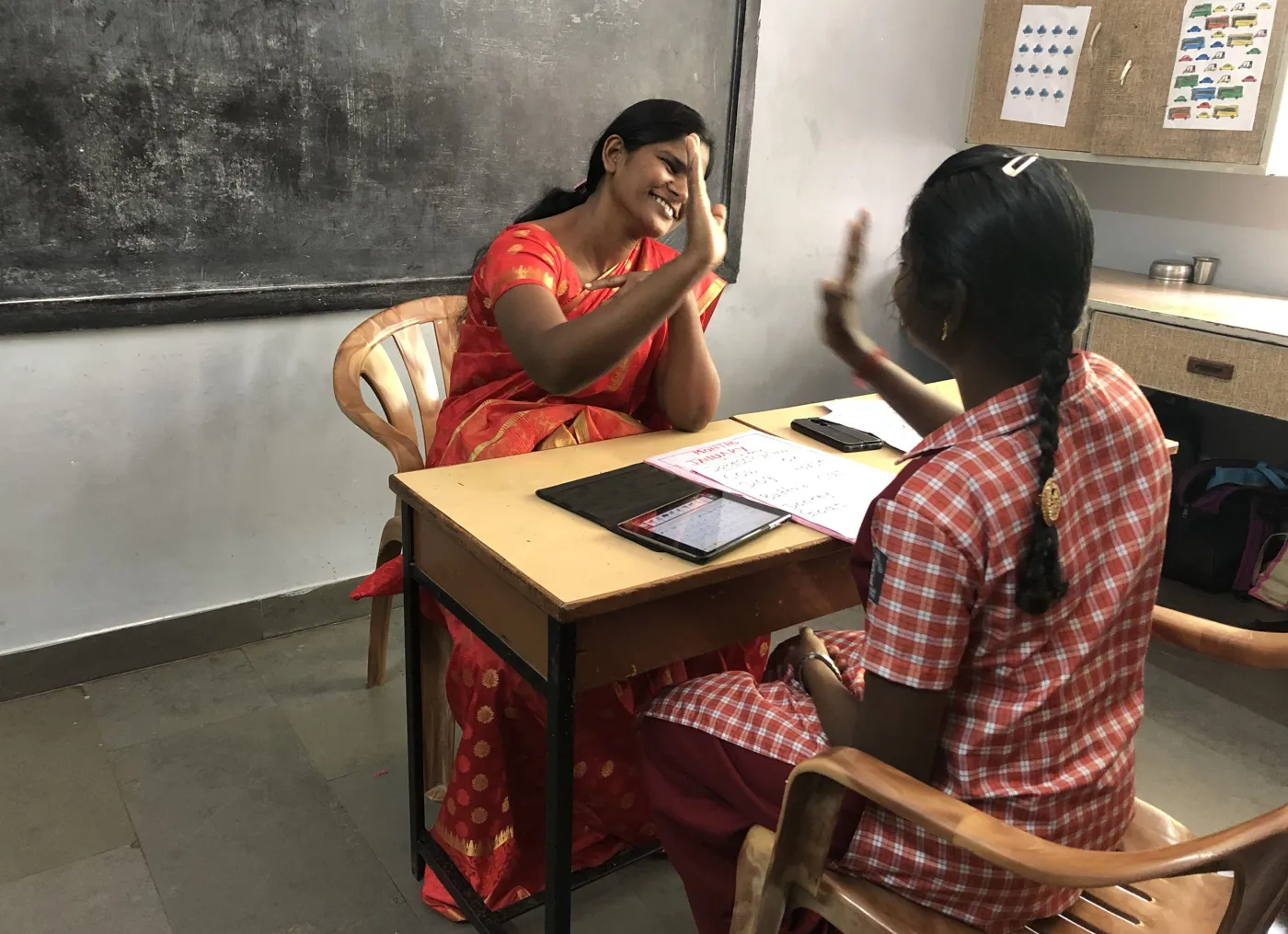 A teacher and student high-fiving in a classroom